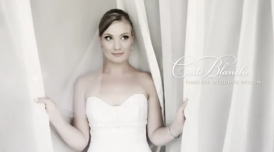 Elegant bride in classic white gown with soft lighting and serene expression.